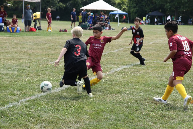 Cinematic shot of a soccer ball on a turf pitch during a rainy training evening.