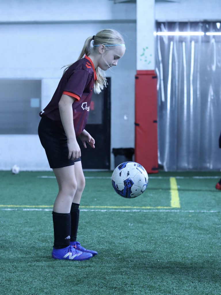 female youth soccer player kicking ball