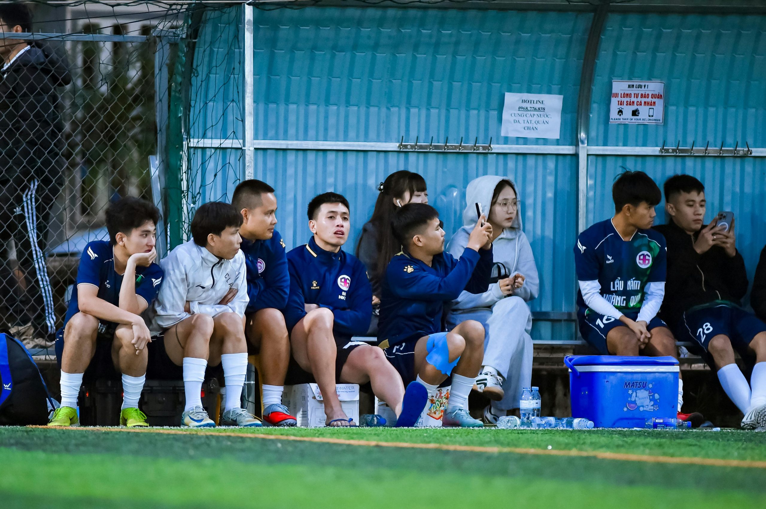 A focused youth soccer player sitting on the bench during a competitive game, reflecting on playing time.